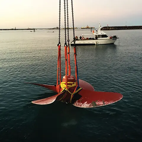 Bronze propeller being lifted clear of the water by crane